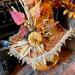 This is a close-up picture of the Halloween witch hat. It shows the hat with fall leaves, an orange pumpkin, and dried botanicals.